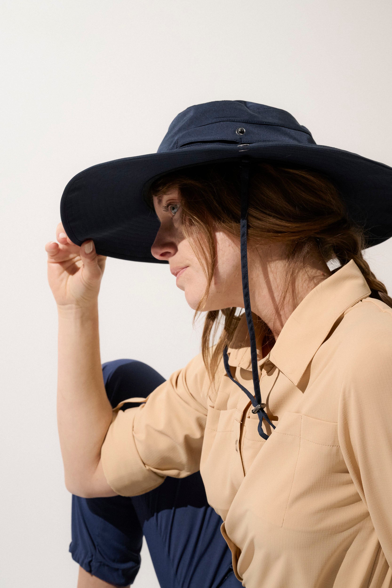 Chapeau anti-UV sombre UPF 50+ porté par une femme, idéal pour les randonnées en pleine nature.