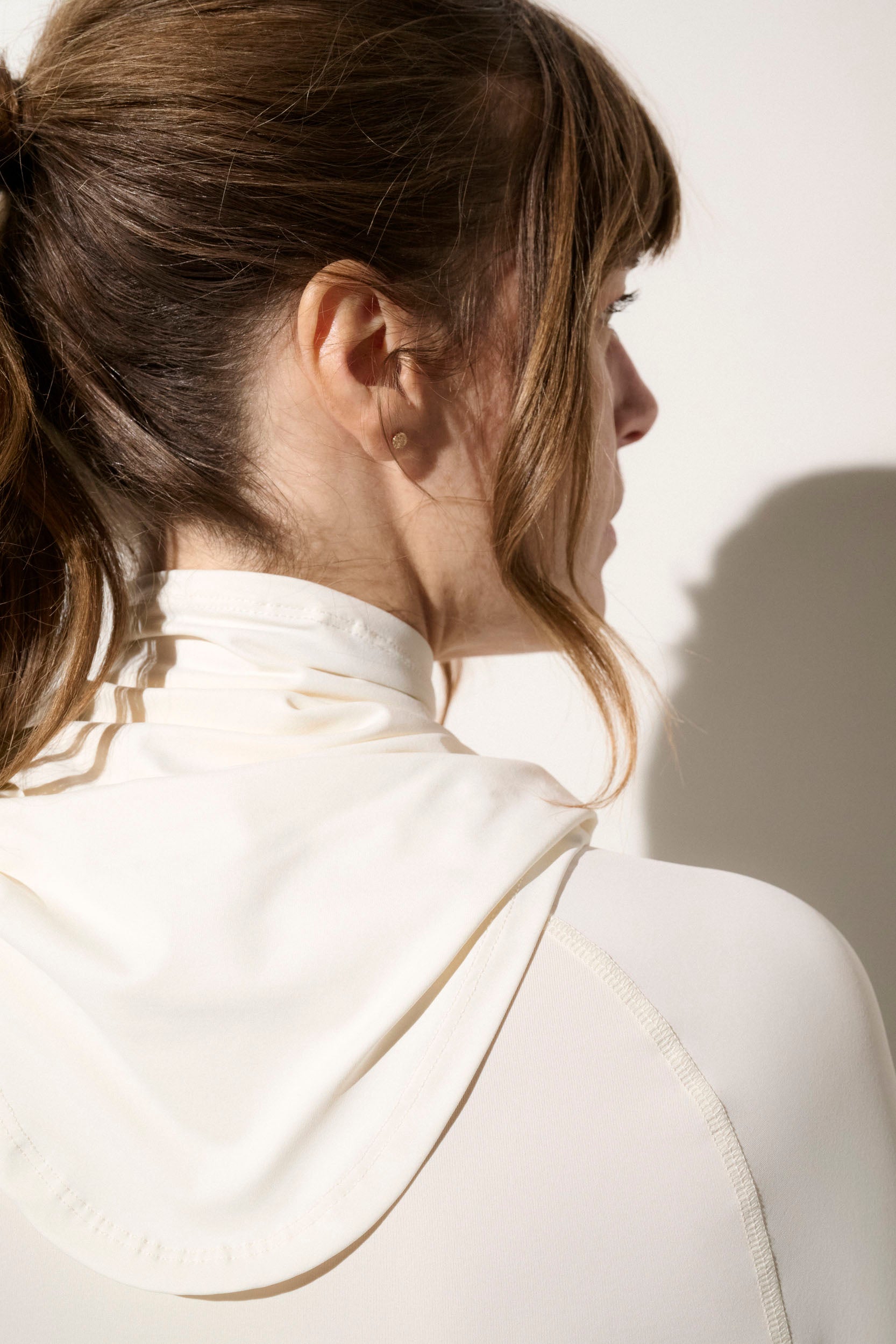 Femme portant un tour de cou anti-UV blanc UPF 50+, tissu léger et respirant, idéal pour activités en plein air.