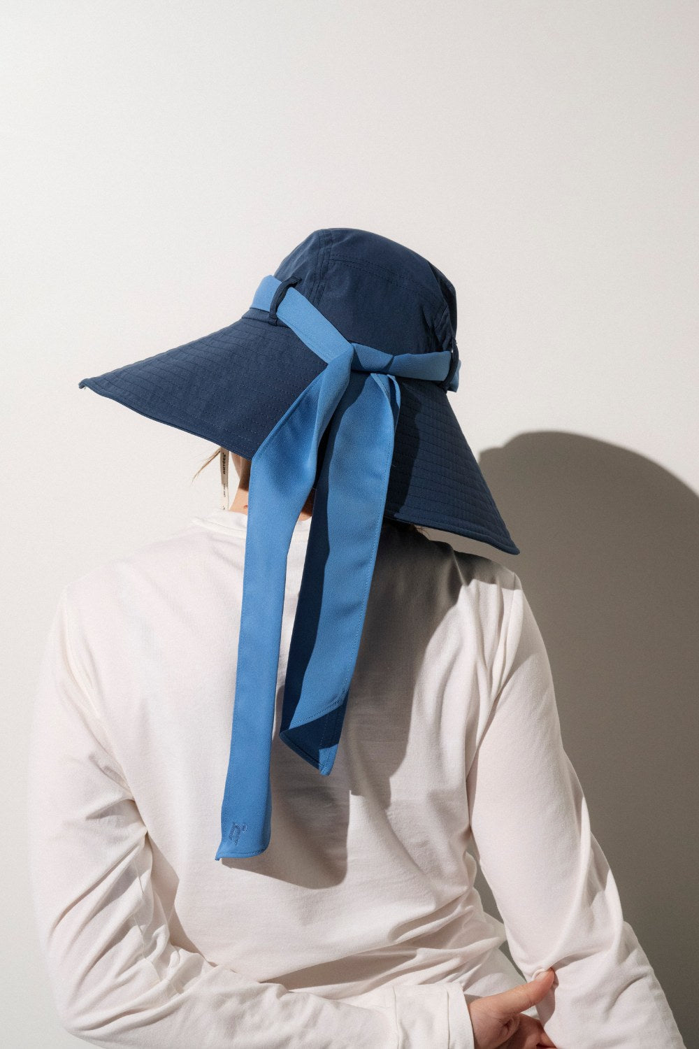 Femme portant un chapeau large anti-UV certifié UPF 50+, idéal pour la protection solaire à la plage et partout ailleurs.