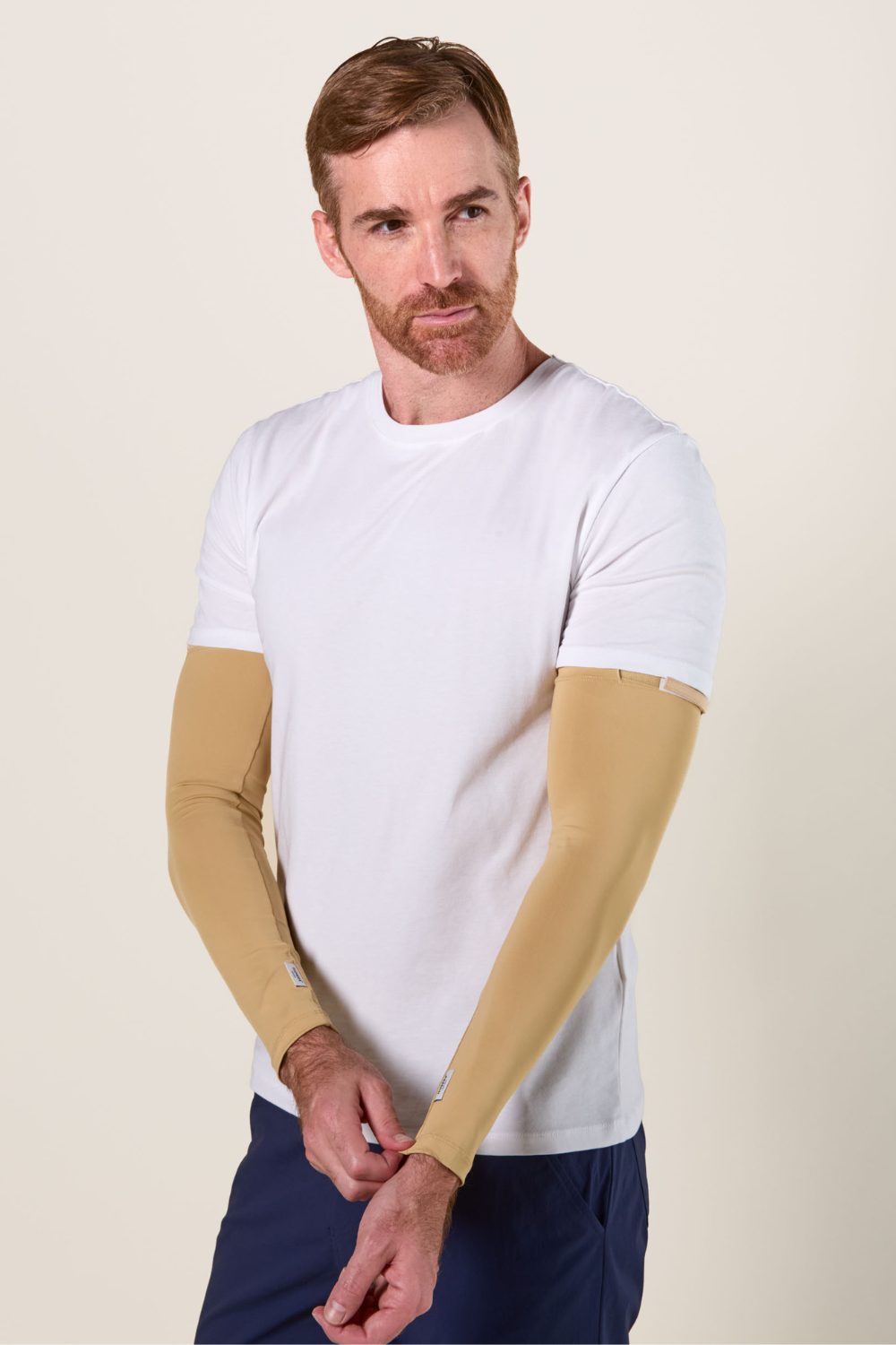Homme portant des manches anti-UV beige UPF 50+, confortables et légères, idéales pour une protection solaire.