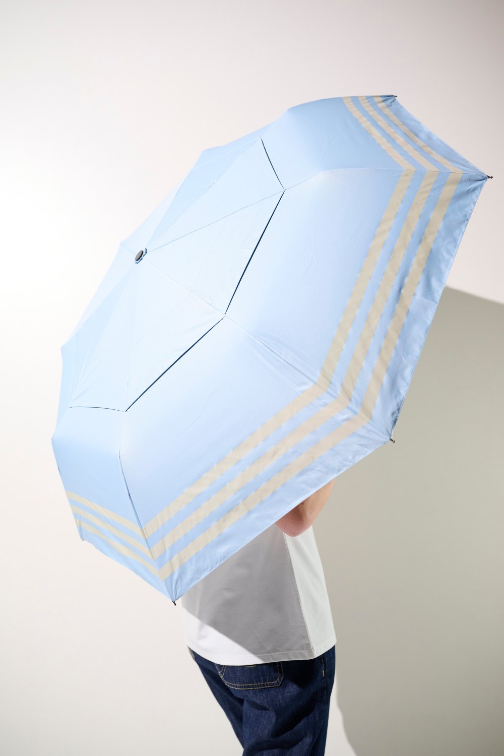 Femme vue de dos tenant une ombrelle anti-UV pour se protéger efficacement du soleil au quotidien.