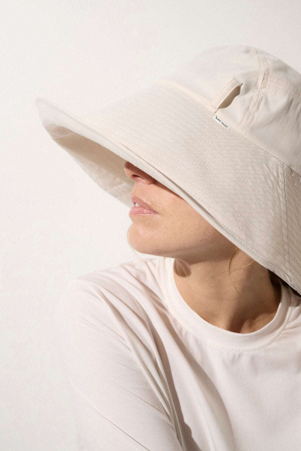 Chapeau anti-UV blanc perlé pour femme, offrant une protection solaire élégante avec large bord.