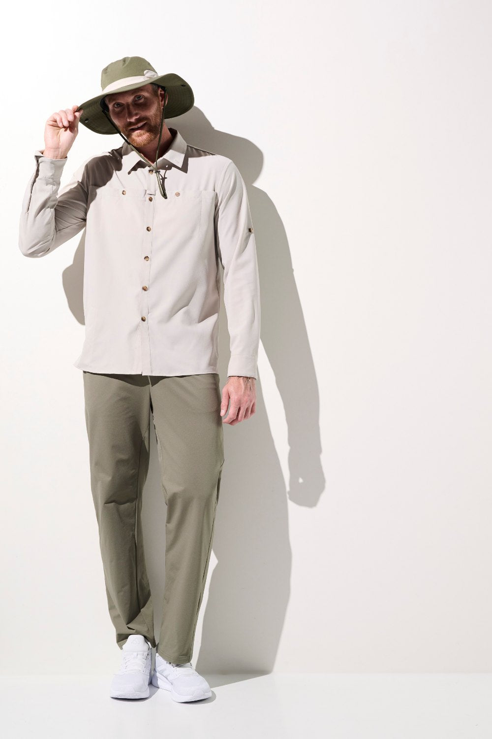 Homme portant une chemise anti-UV beige et un chapeau, conçu pour la protection solaire, idéal pour les activités de plein air.