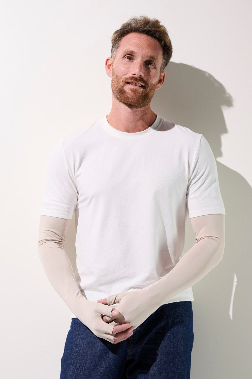 Homme portant des mitaines à manches longues anti-UV en beige, tissus légers, protection solaire UPF 50+.