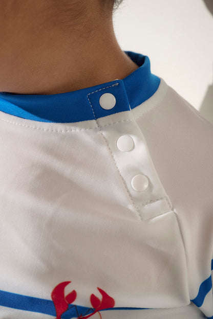 T-shirt de bain anti-UV blanc pour enfant de Nuvées, avec boutons pressions pour un enfilage facile et protection solaire.